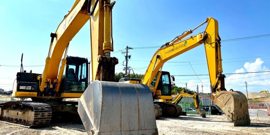建設現場に並ぶ2台の大型ショベルカーの実物写真。重機や大型機械の出張買取品目として紹介。